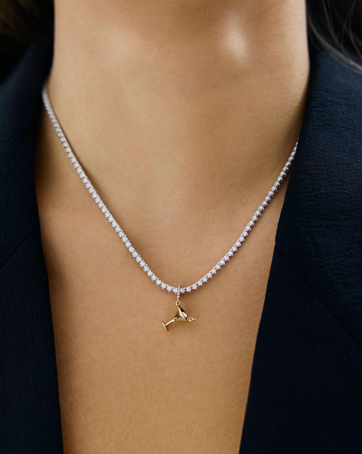 Detailed view of dirty martini charm being worn with diamond necklace around model's neck