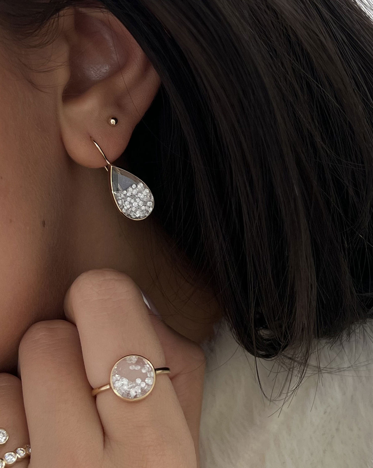 Detailed view of model wearing Shaker Pear Drop Earring on ear paired with our Shaker Round Ring on finger.