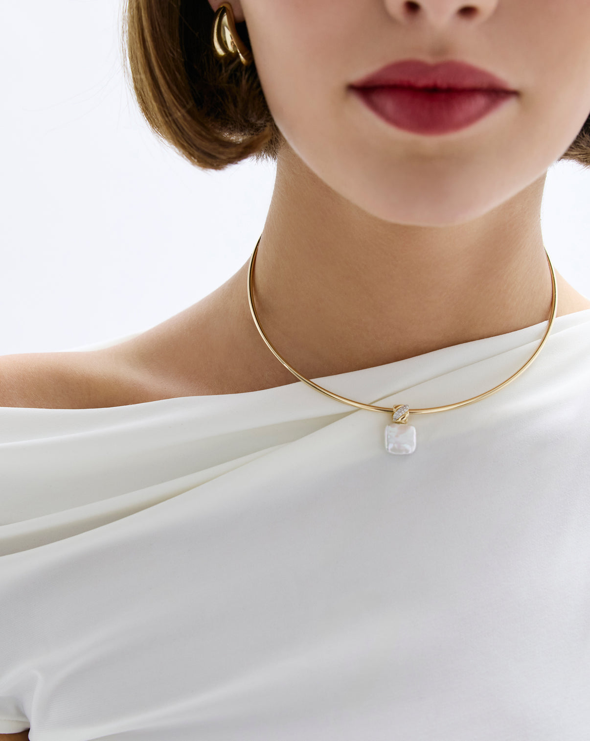 Model wearing square pearl pendant with gold necklace.