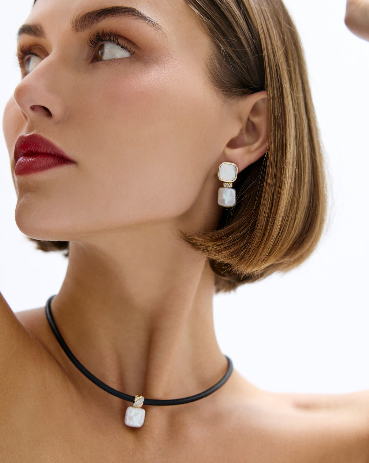 Model wearing square pearl earrings showcasing 16 round natural diamonds.
