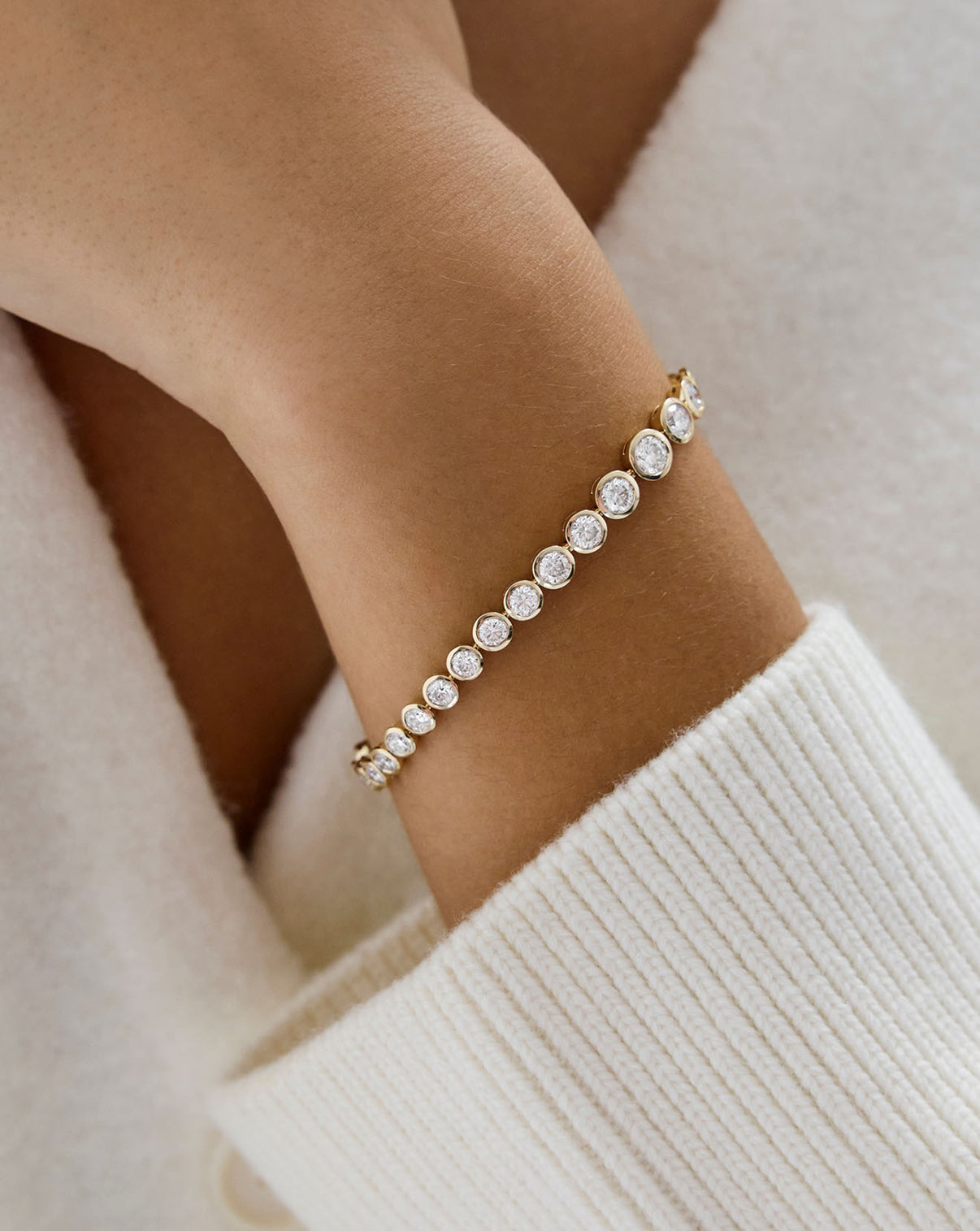Close up view of graduated bezel round lab diamond 14k gold bracelet being worn on wrist