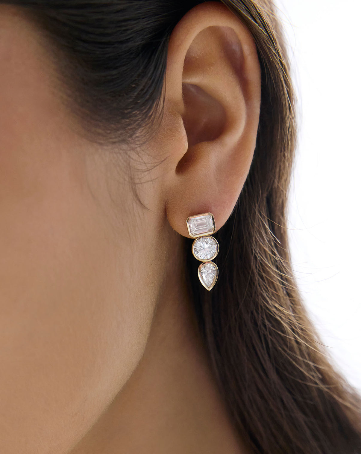 Detailed view of 14k solid gold 3 stone lab diamond multi-shape drop earring worn on ear