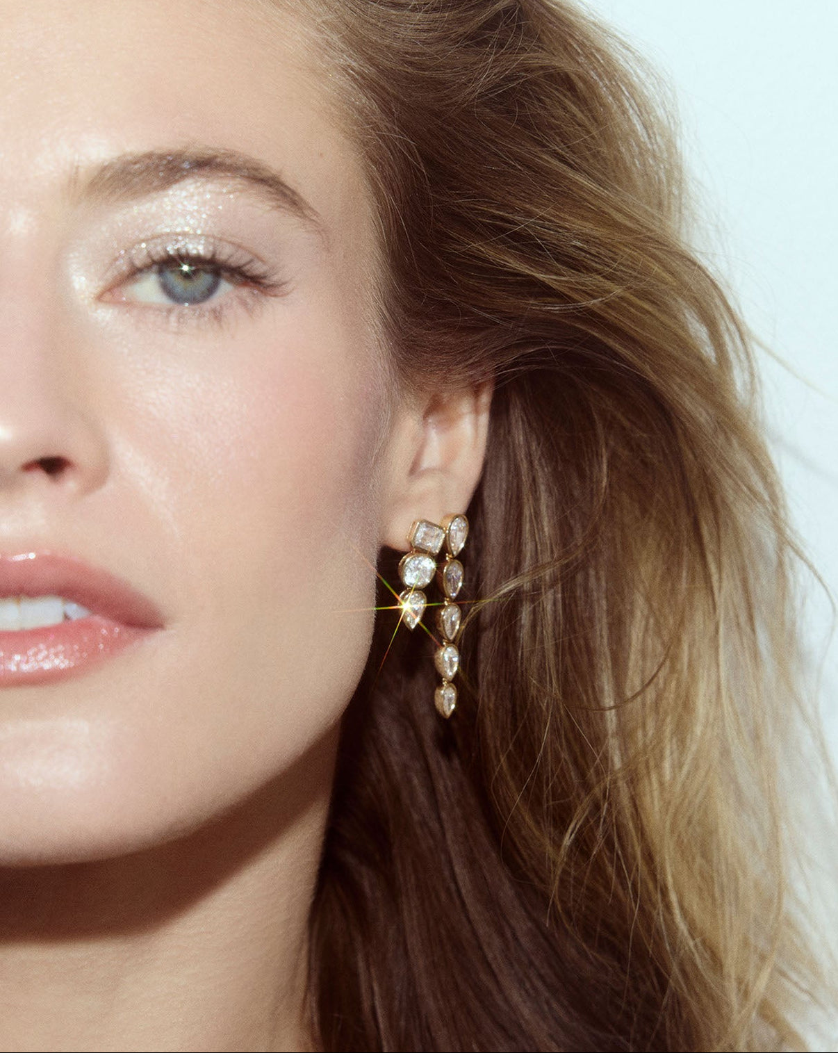 Front view of 14k gold multi-shape drop earrings with lab grown diamonds worn on ear paired with the ring concierge pear long drop earrings