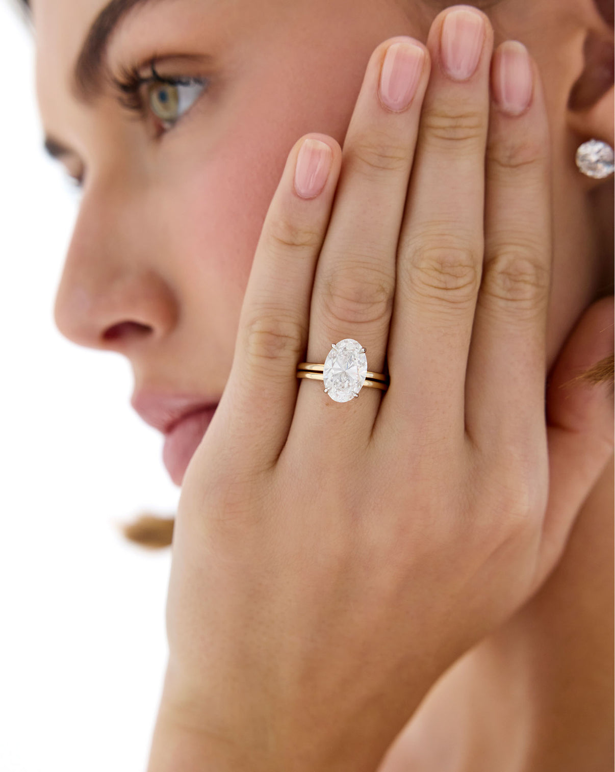 Model wearing 14K Yellow Gold Whisper Thin Band stacked with Oval Engagement Ring