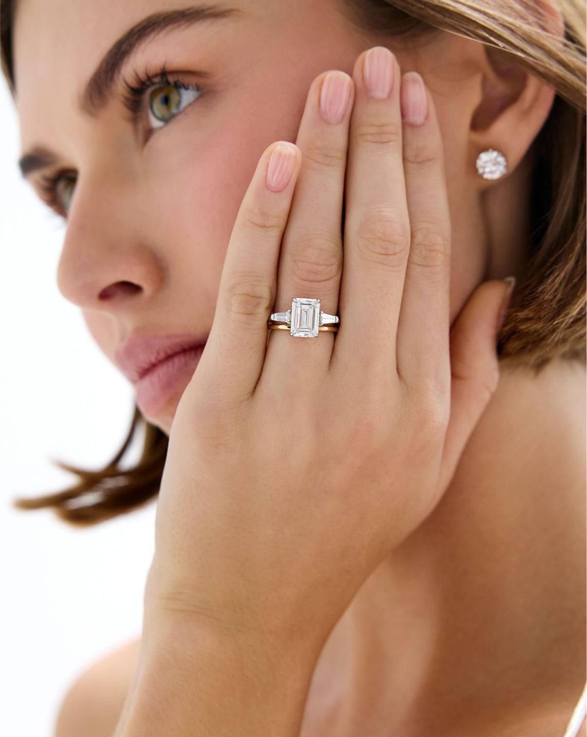Model wearing 14K Yellow Gold Whisper Thin Band stacked with Emerald Three Stone Engagement Ring