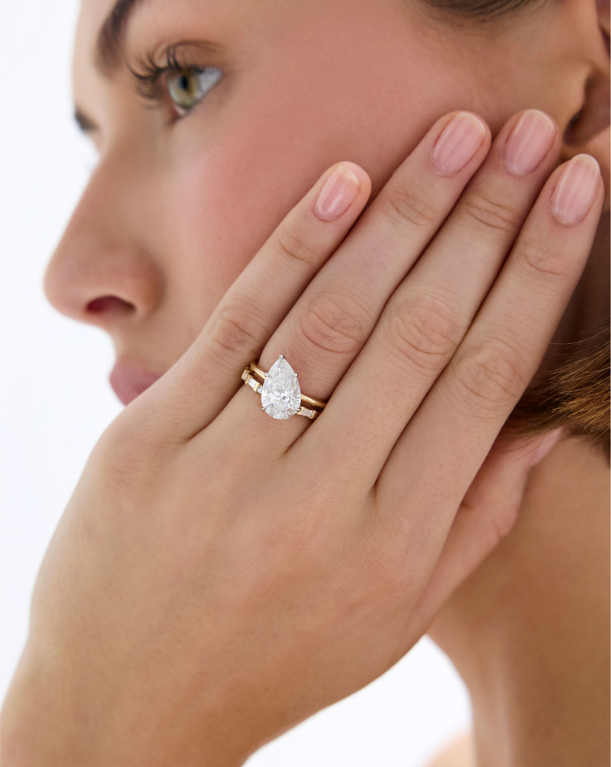 model wearing Baguette Bar Diamond  Eternity Band in 14k Yellow gold stacked with an off-center pear diamond engagement ring set in whisper thin