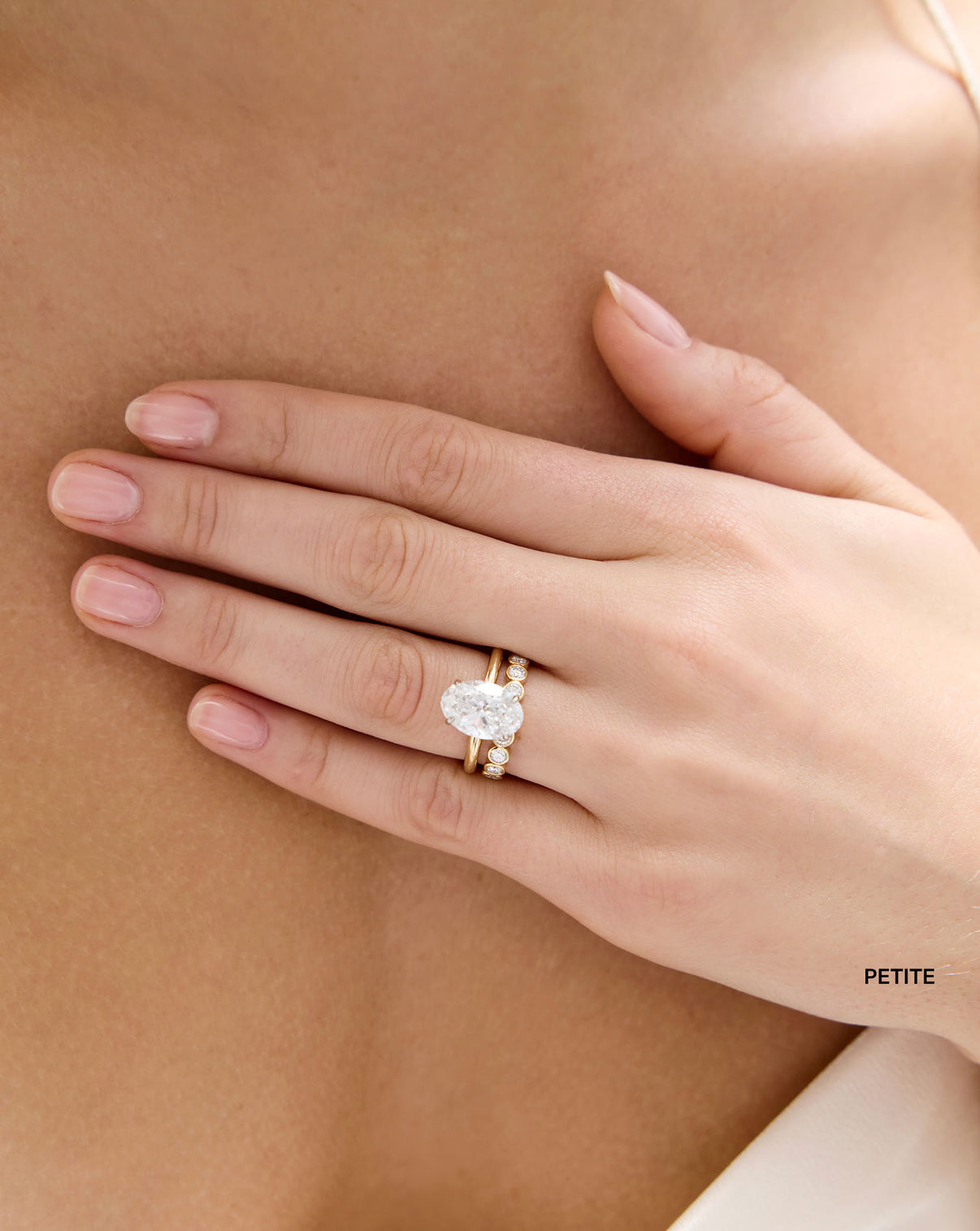 model wearing Petite 1.5 Carat Weight Diamond Round Bezel Eternity Band ring in stacked with Oval Engagement Ring in Whisper Thin global