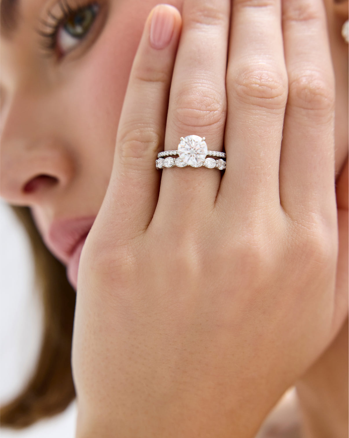 Model wearing Sideways Oval Diamond Eternity Band in Platinum stacked with a Round Engagement Ring set in Whisper Thin Pave global