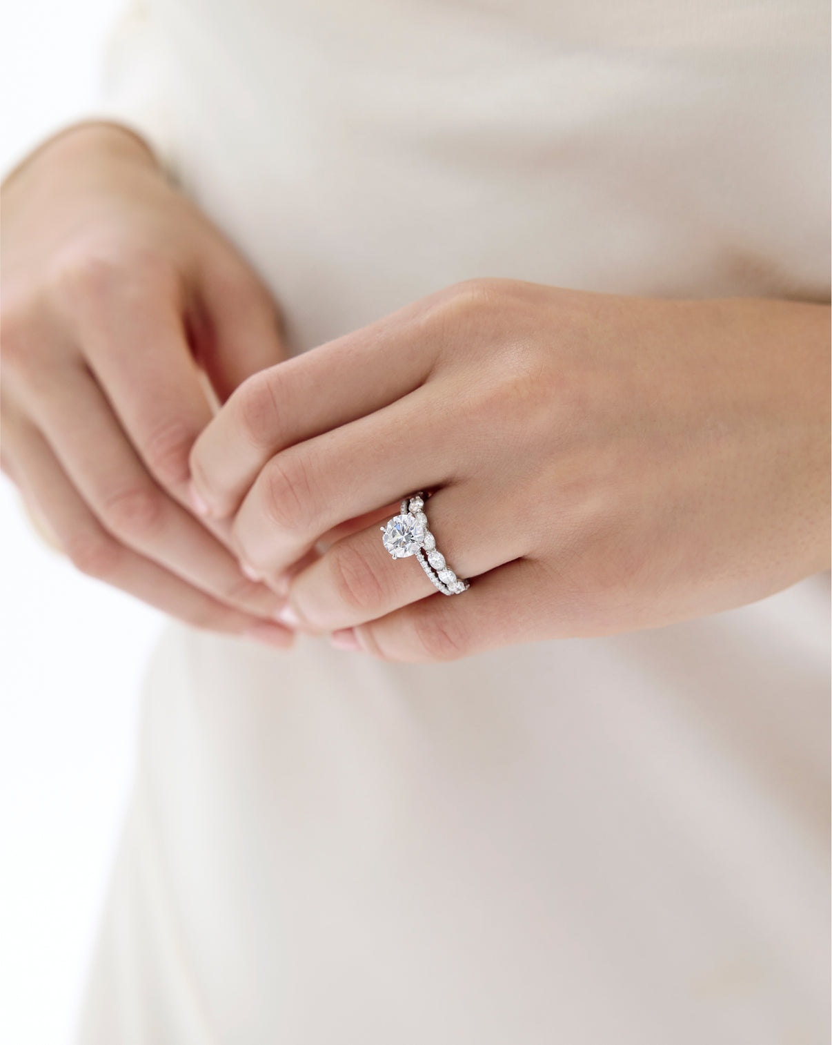 Model wearing Sideways Oval Diamond Eternity Band in Platinum stacked with a Round Engagement Ring set in Whisper Thin Pave global