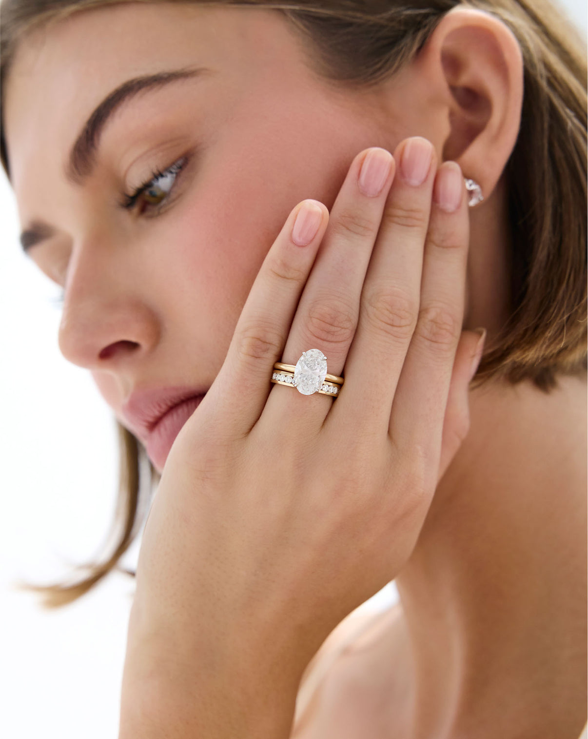 model wearing Round Diamond Channel Set Band ring in 14K Yellow Gold stacked with Oval Engagement Ring set in Whisper Thin
