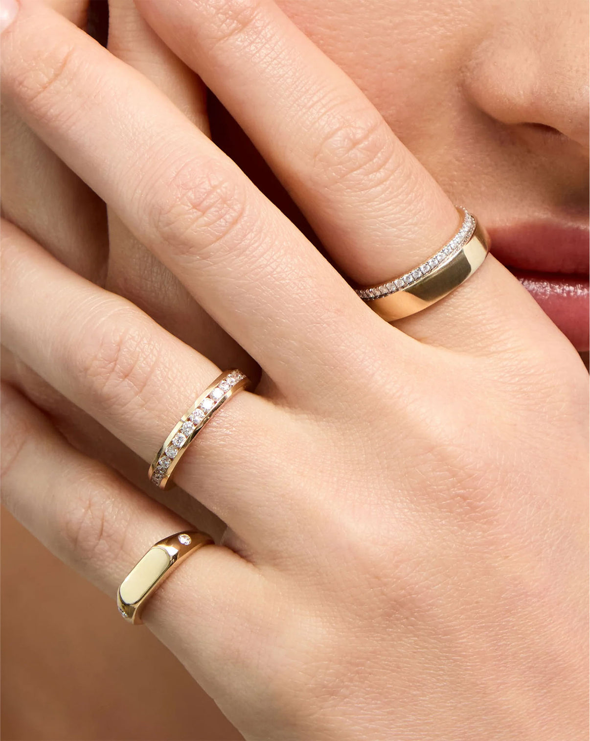 Model wearing Round Diamond Channel Set Band ring in 14K Yellow Gold styled with other gold and diamond rings