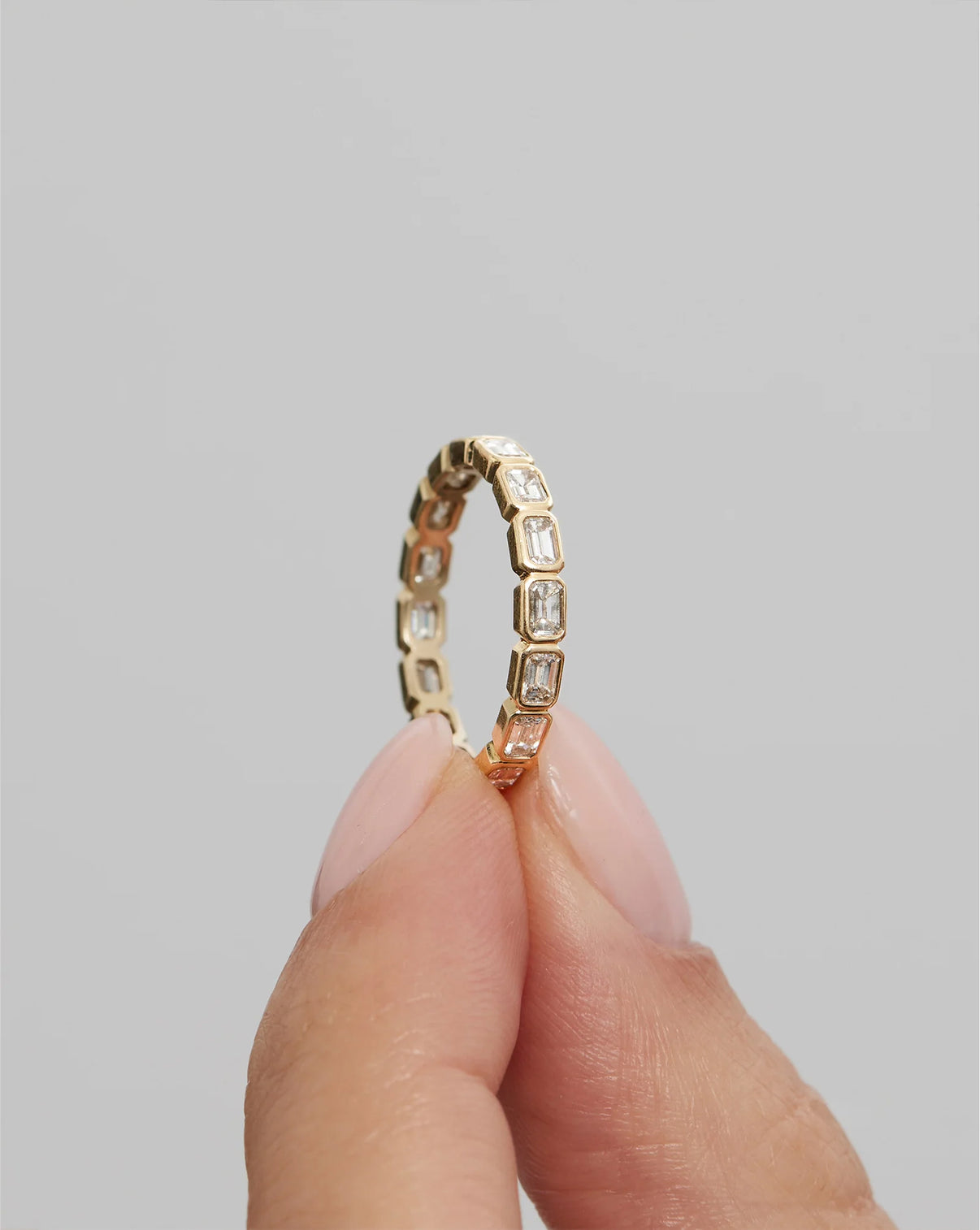 Model holding 14k Yellow Gold Sideways Emerald Bezel Eternity Band global