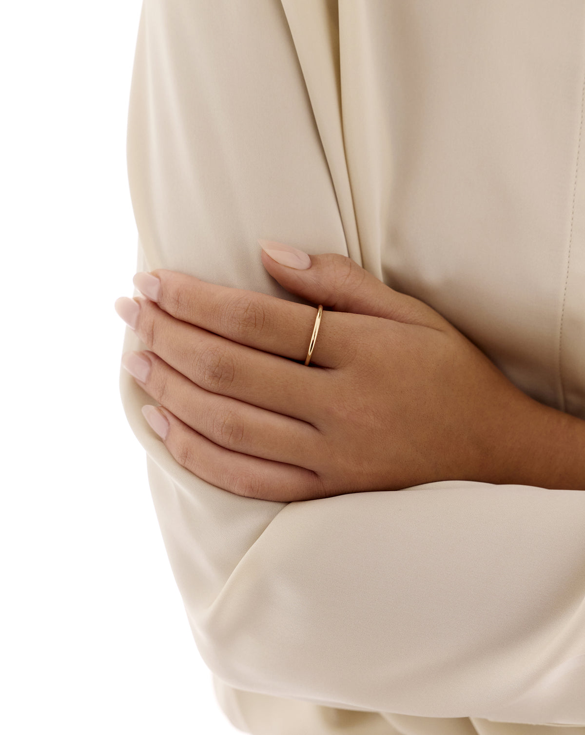 Close-up of a hand wearing the 14k yellow gold Classic Stackable Ring on the index finger, resting on the opposite arm over a cream blouse. 14K Yellow Gold Sterling Silver