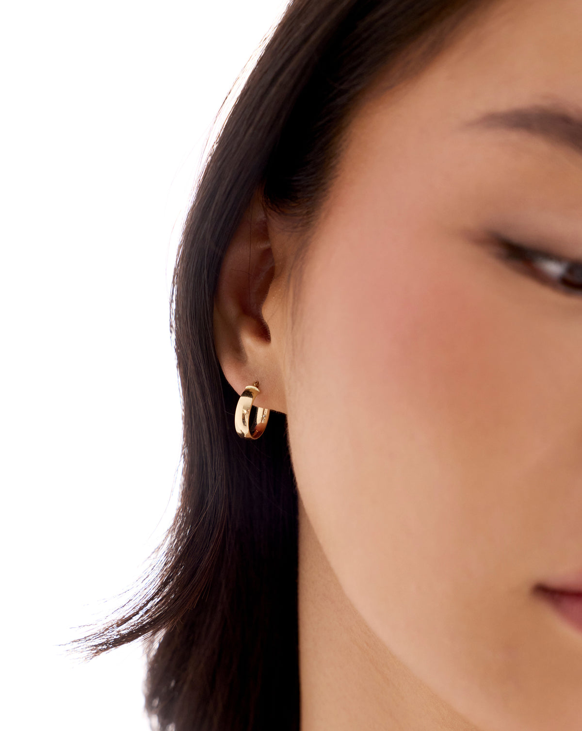14k yellow gold wide mini hoop earring worn on the ear, featuring a smooth rounded design and hinged closure. global