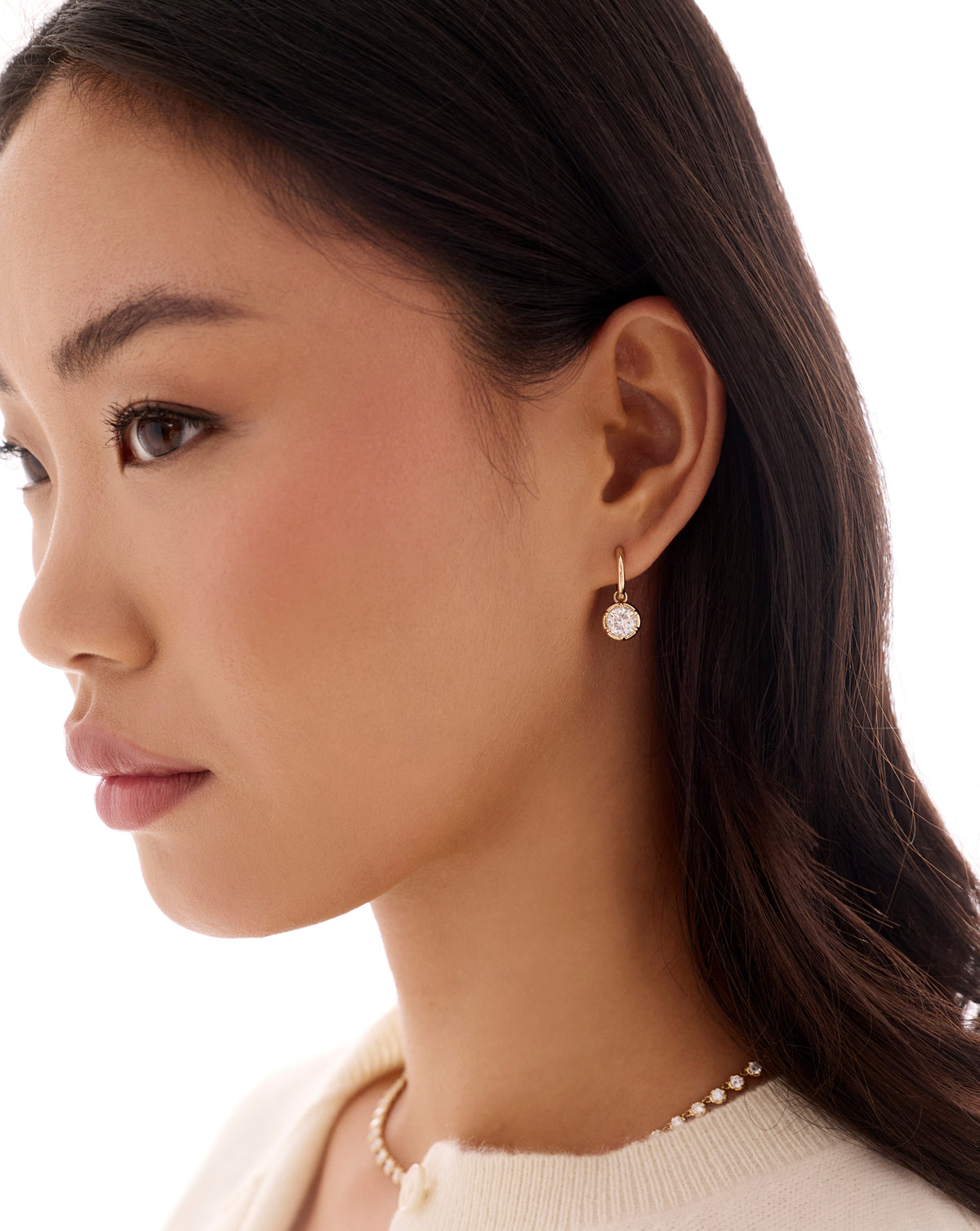 Side profile of woman wearing a 14k gold drop earring with a round diamond, paired with a delicate diamond necklace global