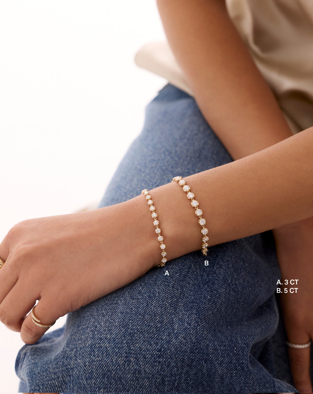 3 and 5 carat Gold tennis bracelet with sparkling round-cut stones worn on the wrist, styled with denim jeans.
3 ct 44299697225816, 44299697586264