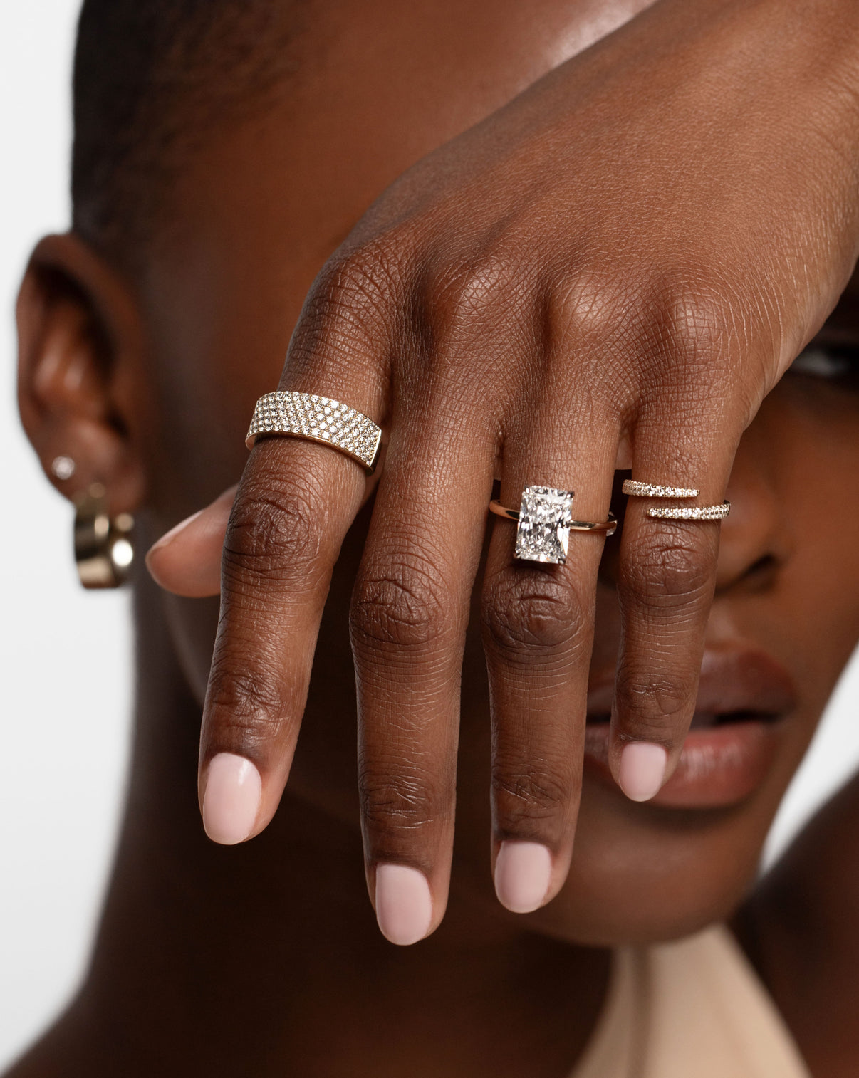 14k gold and diamond five row diamond ring, radiant cut diamond engagement ring, and diamond and gold wrap ring on model