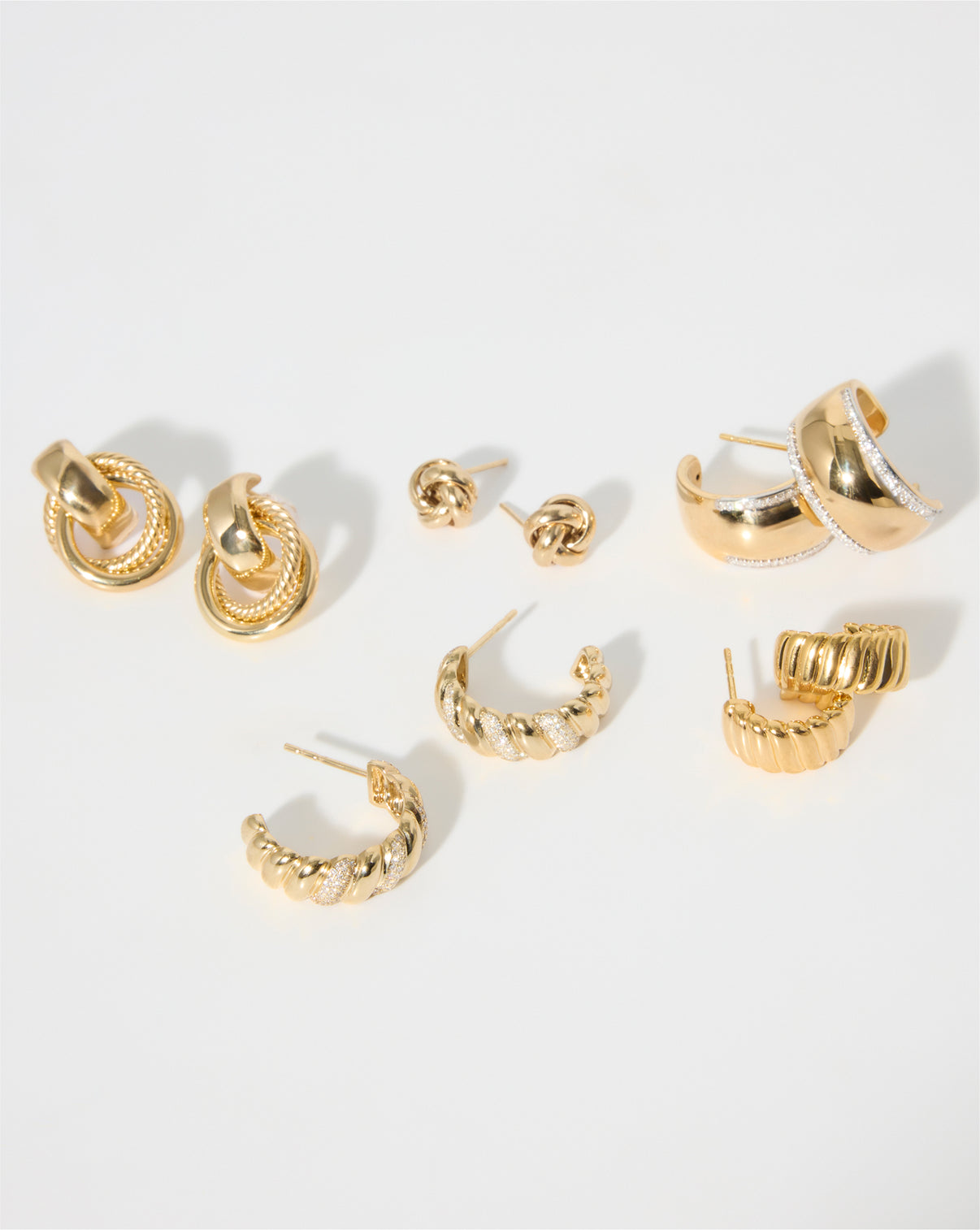 Flat lay of multiple pairs of earrings in yellow gold