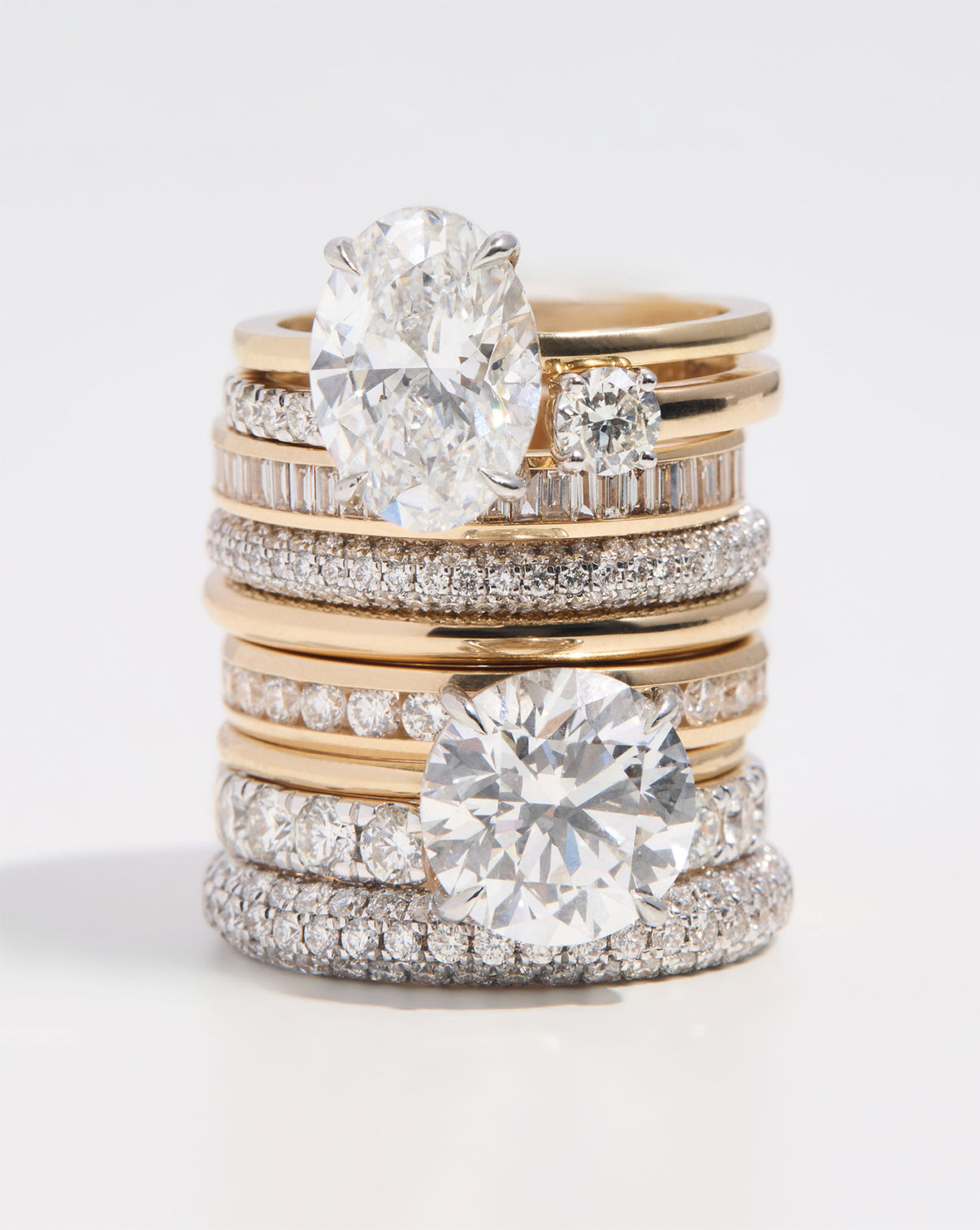 assorted engagement rings and wedding bands stacked on each other on white background global