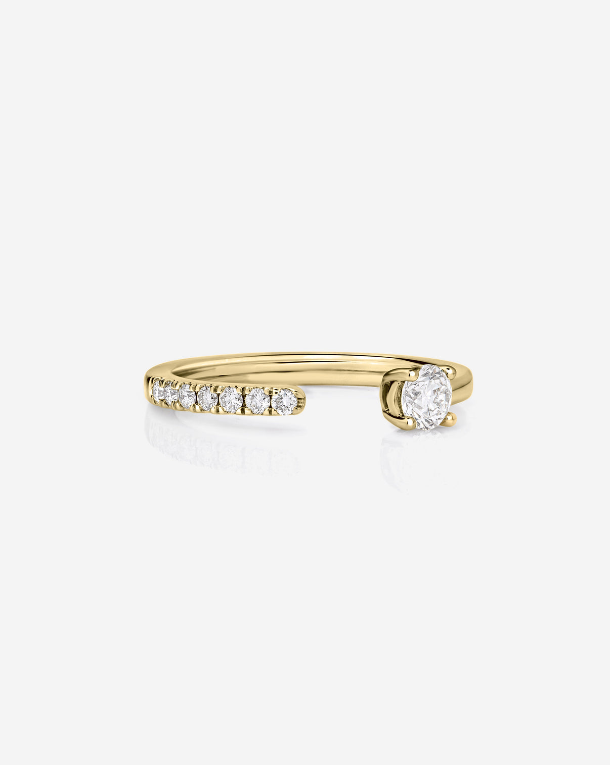A 14k yellow gold open band ring featuring ak row of small round-cut diamonds on one side and a larger oval diamond on the other, set against a clean white background.