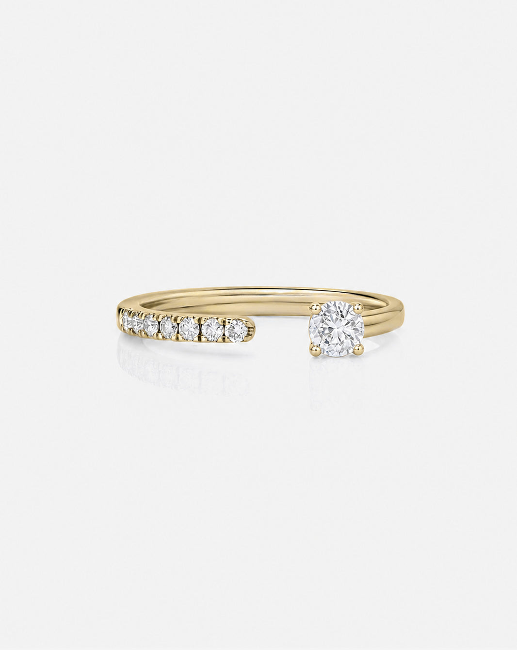 A yellow gold split ring featuring a row of small round-cut diamonds on one side and a larger round-cut diamond on the other, set against a light gray background. 14k yellow gold