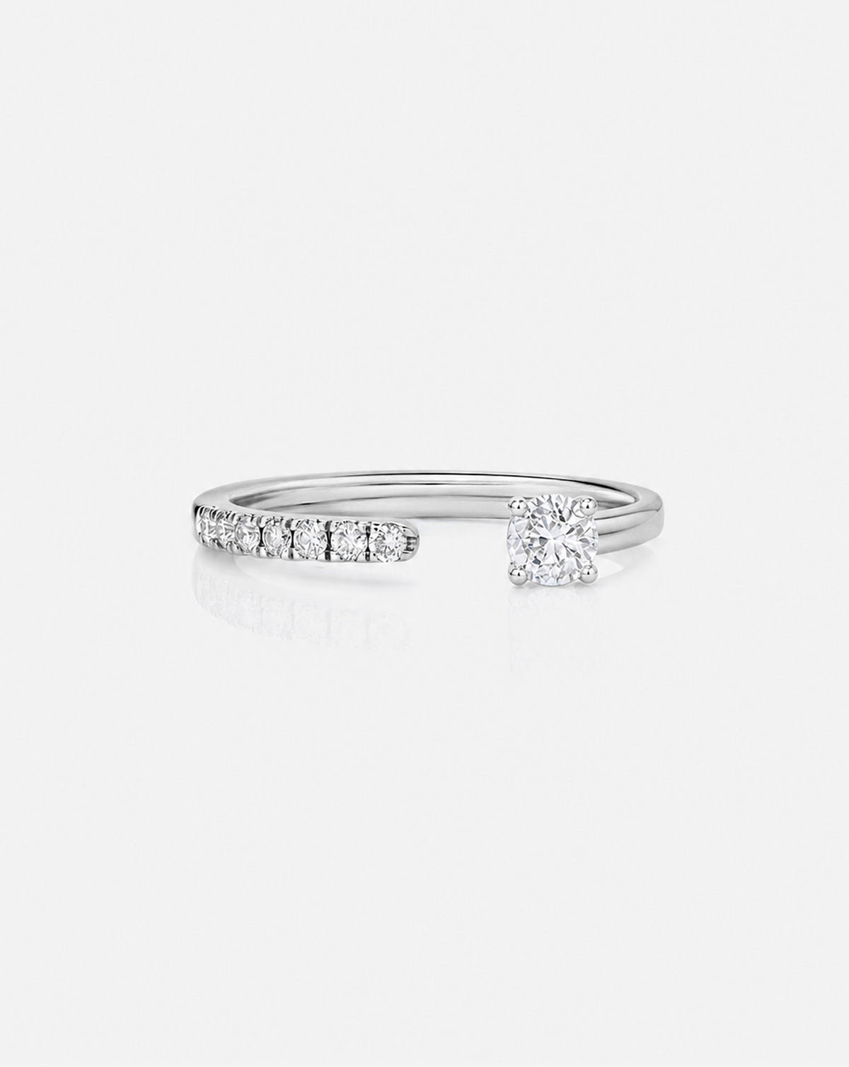 A 14k white gold platinum open band ring featuring a row of small round-cut diamondson one side and a larger center stone on the other, shown on a light gray background.