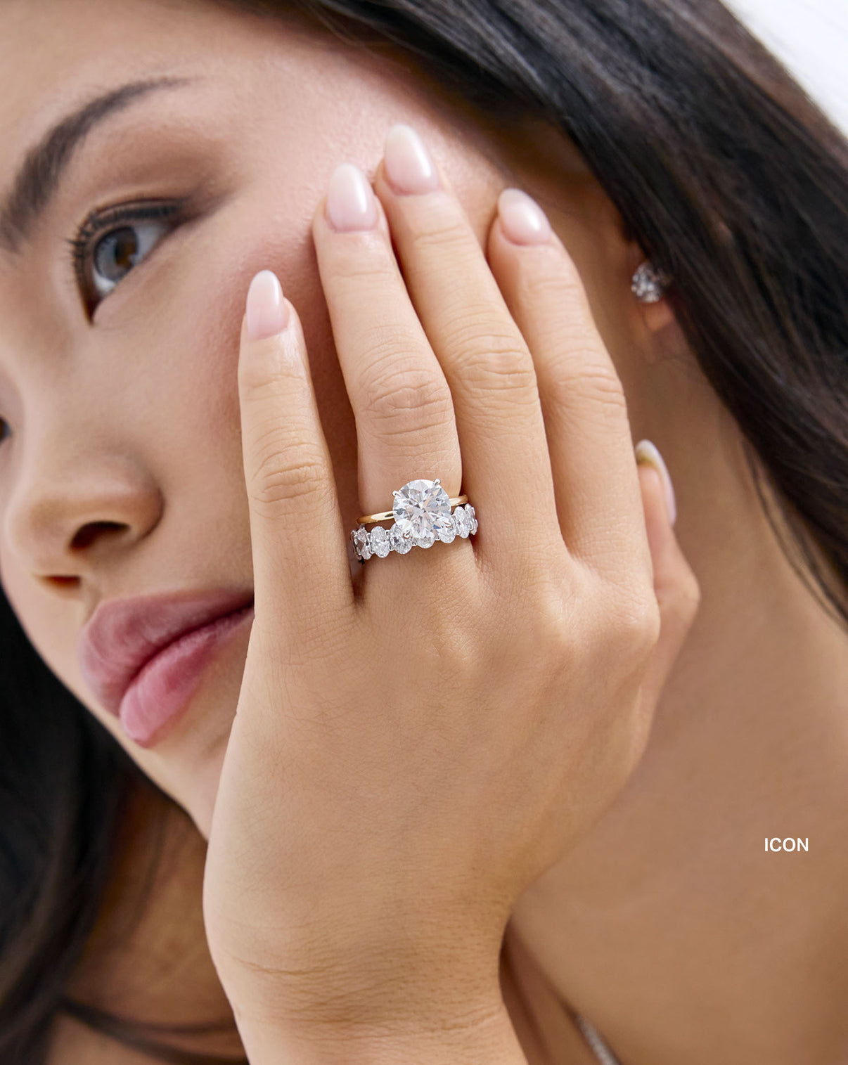 close up of a woman's hand wearing oval icon eternity band with round engagement ring global