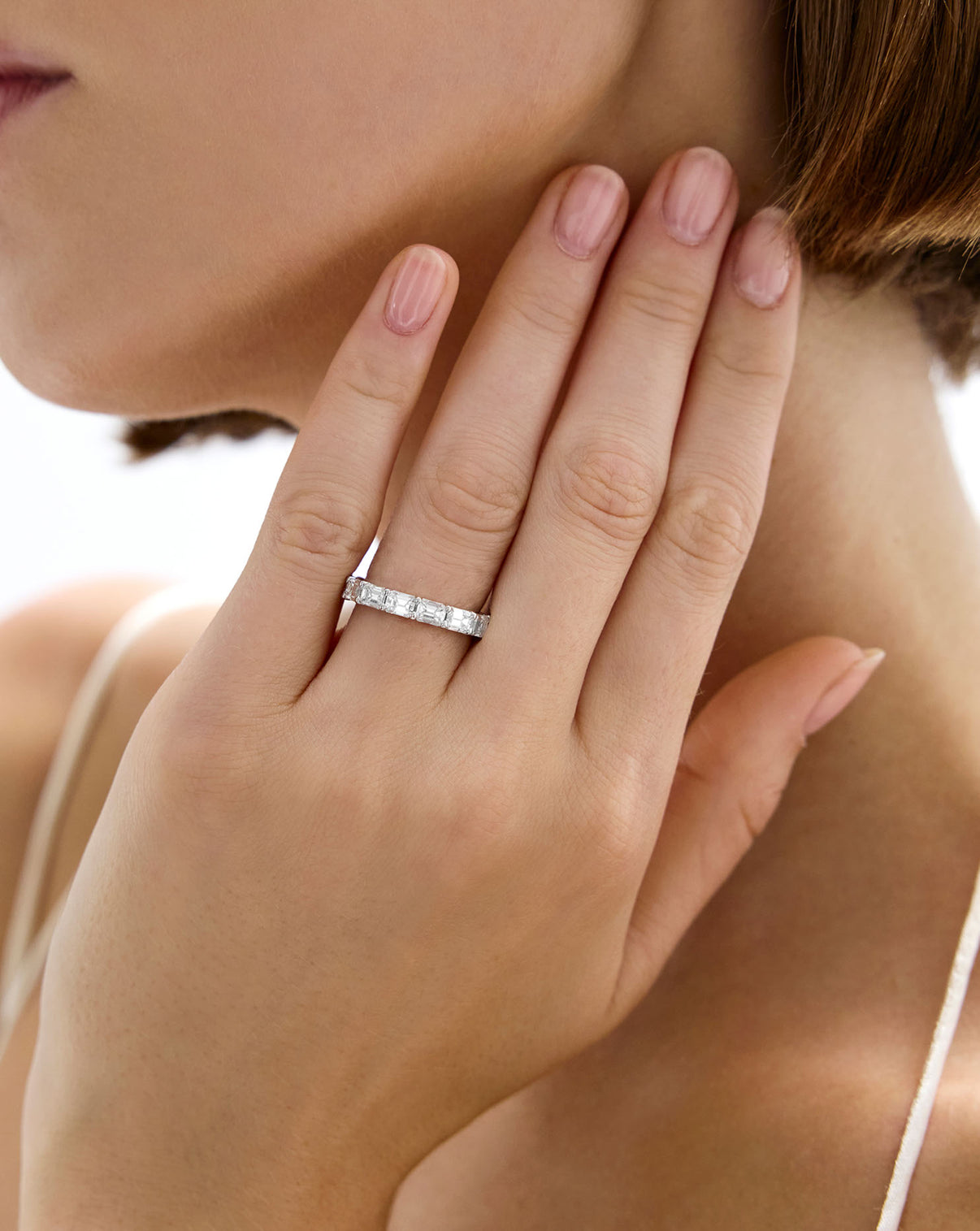 Close-up of a hand wearing a Diamond Sideways Emerald Eternity Band global