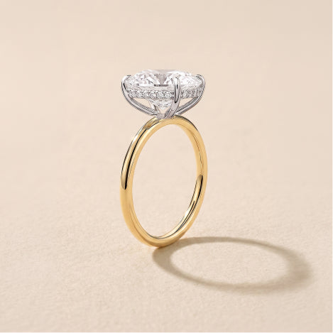 yellow gold round diamond engagement ring hidden halo against a neutral textured background