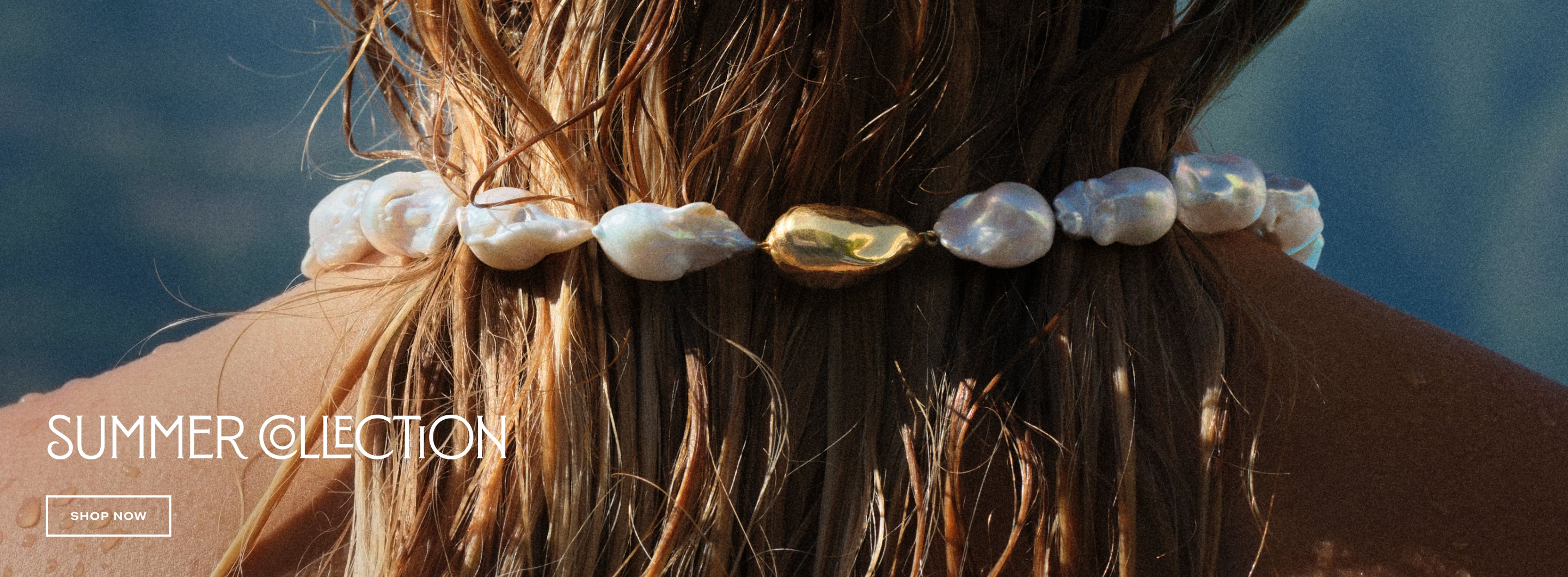 close up of the baroque pearl necklace around a model's neck with "summer collection shop now" text overlay