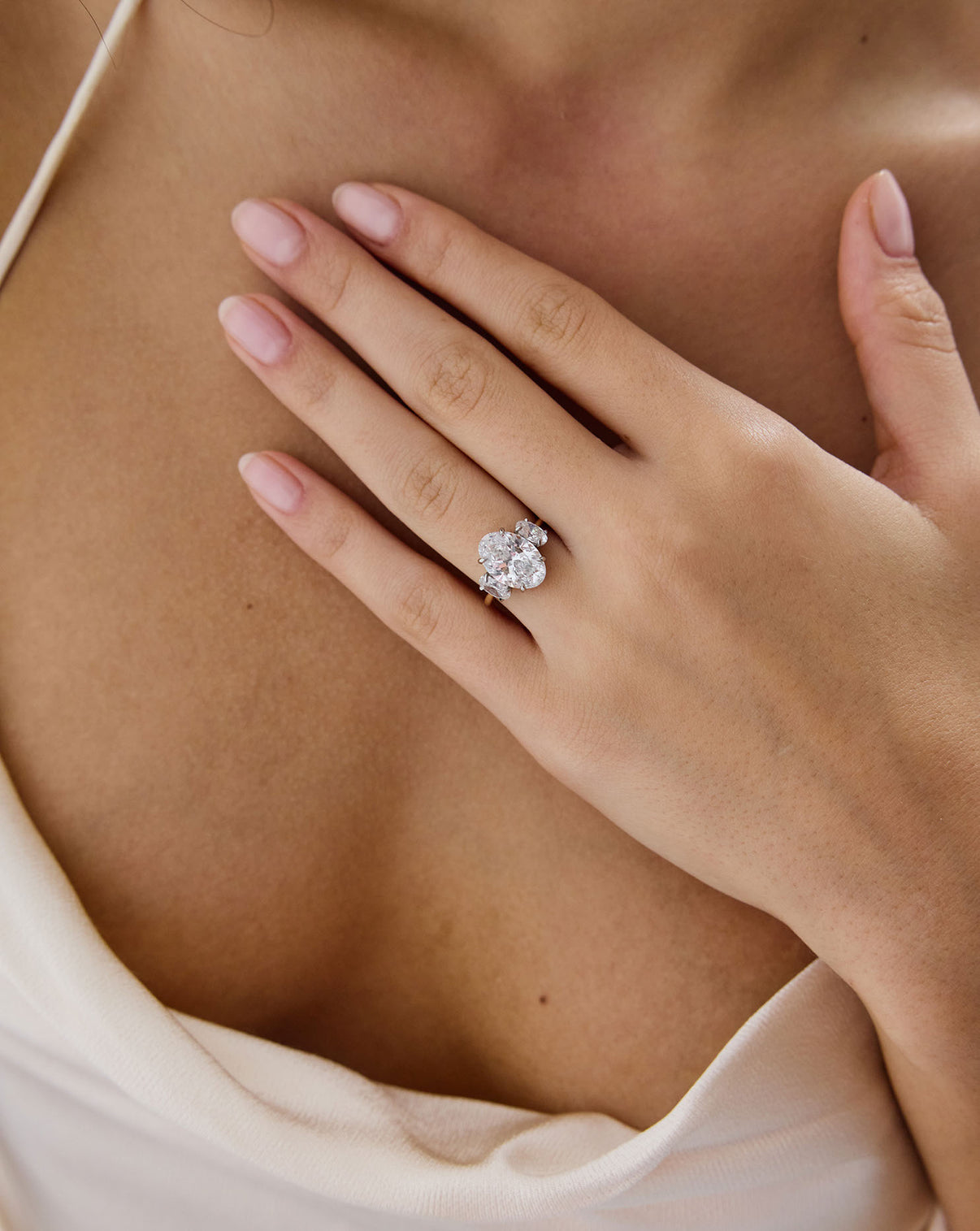 close up of 4 carat Oval Engagement Ring in 14k yellow gold Whisper Thin Three Stone with platinum prongs shown on model's hand