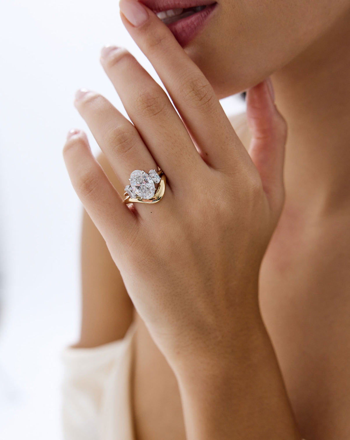 4 carat Oval Engagement Ring in 14k yellow gold Whisper Thin Three Stone with platinum prongs shown on model's hand styled with a curved gold wedding band