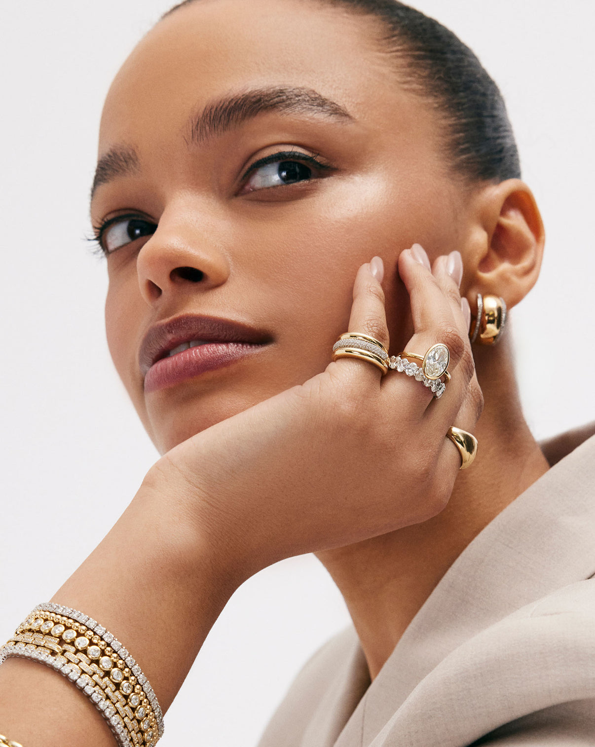 2 carat Oval Diamond Engagement Ring in Yellow Gold Whisper Thin Bezel shown on model's hand and styled with various gold and diamond rings