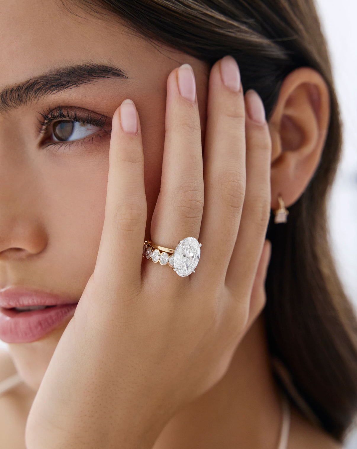 5 carat Oval Diamond Engagement Ring in Yellow Gold Whisper Thin Hidden Halo band with Platinum Prongs styled on model's hand with an oval diamond band
