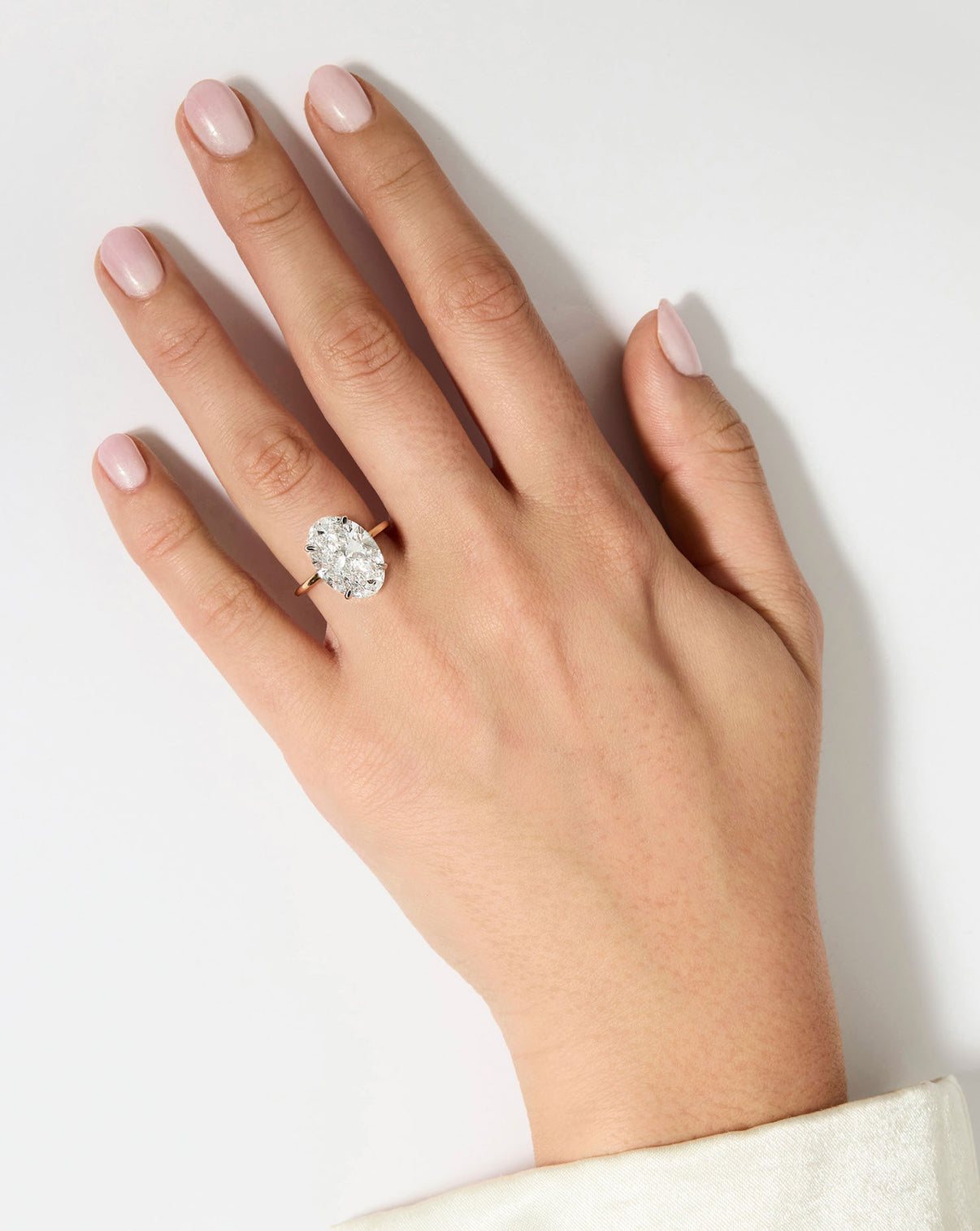 6 carat Oval Diamond Engagement Ring in Yellow Gold Whisper Thin Hidden Halo band with Platinum Prongs shown on hand