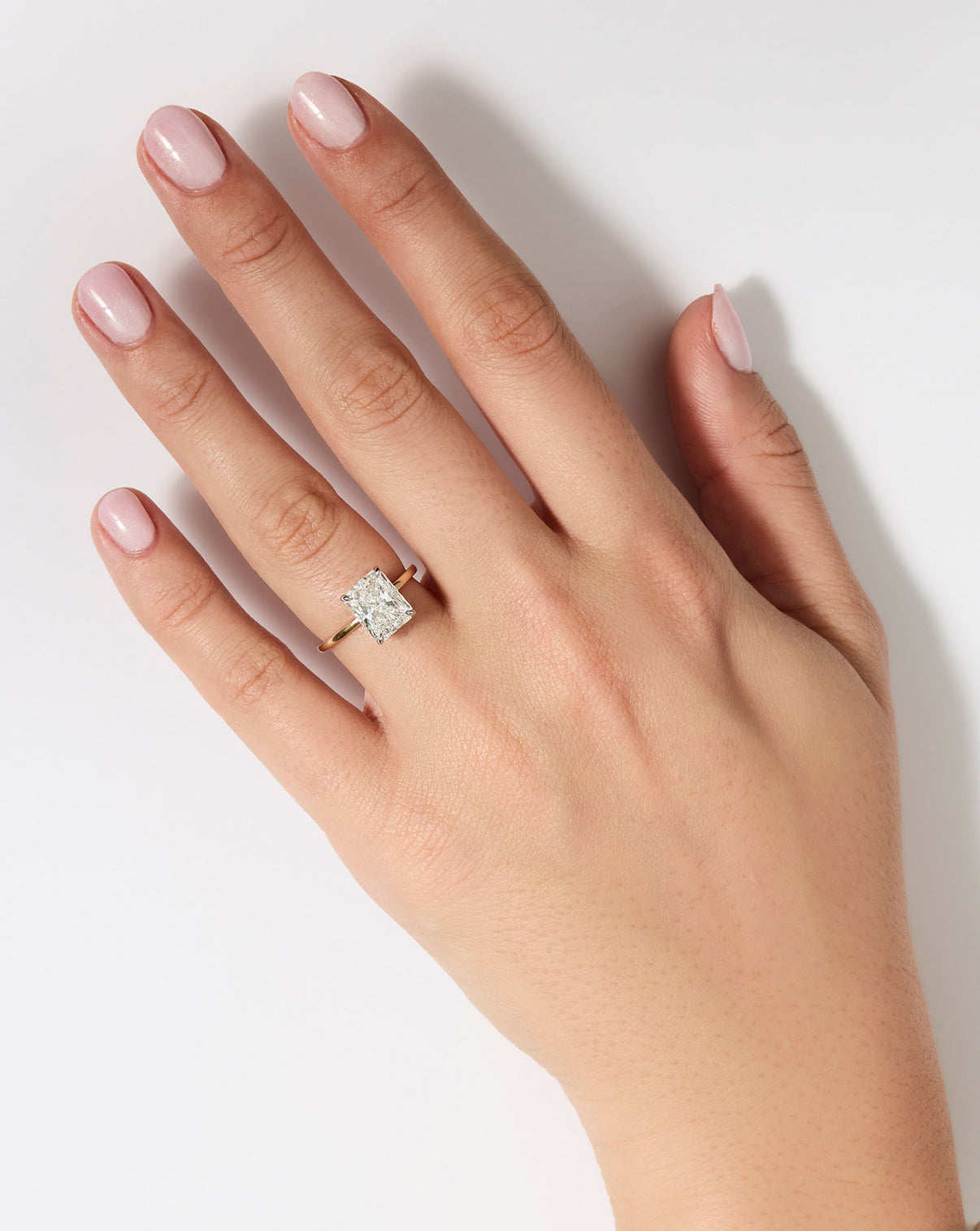 3 carat Radiant cut Diamond Engagement Ring in Yellow Gold Whisper Thin Hidden Halo band with Platinum Prongs shown on hand