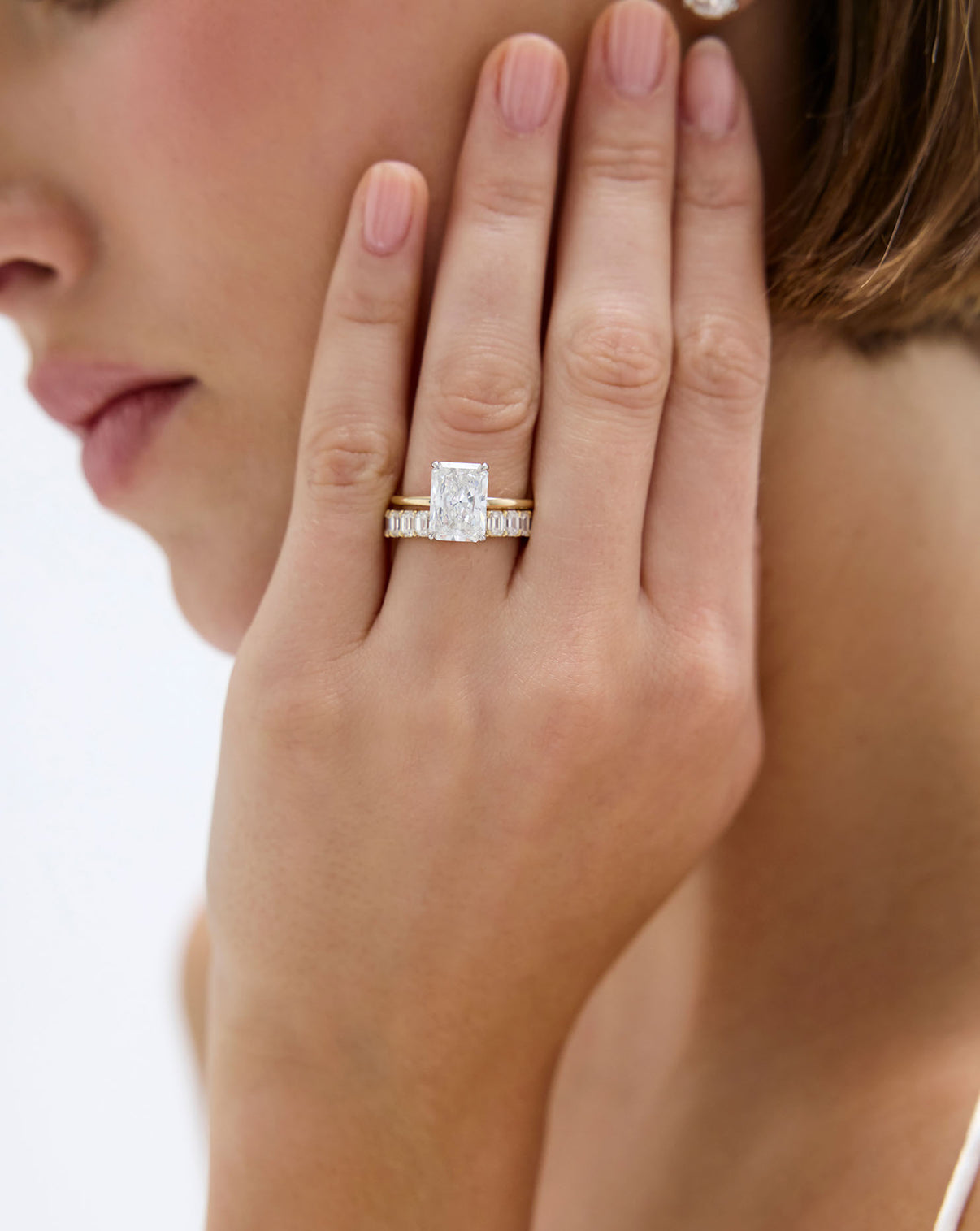 3 carat Radiant cut Diamond Engagement Ring in Yellow Gold Whisper Thin Hidden Halo band with Platinum Prongs styled with diamond wedding band on a model