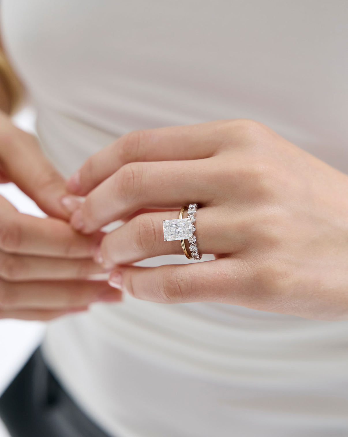 close up of 3 carat Radiant cut Diamond Engagement Ring in Yellow Gold Whisper Thin Hidden Halo band with Platinum Prongs styled with a diamond wedding band