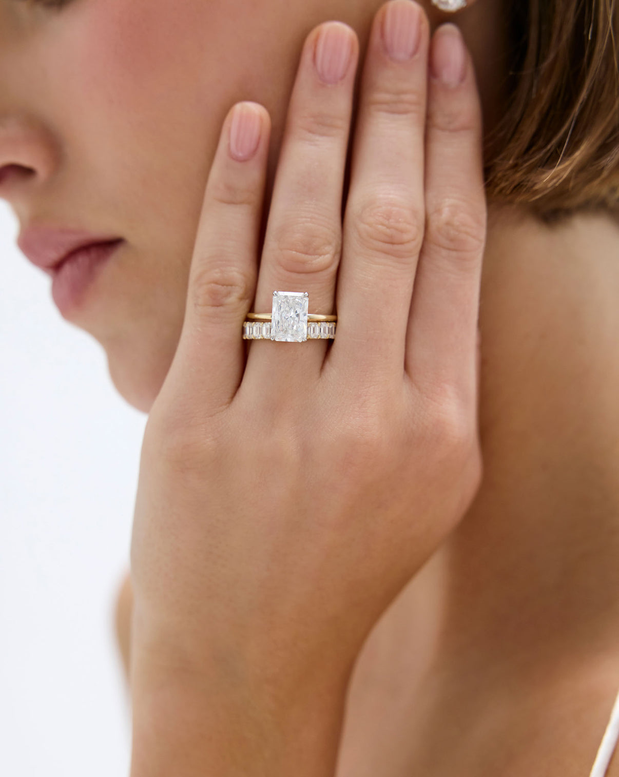 Ring Concierge Engagement Rings | 3 carat Radiant Cut Diamond Ring in Yellow Gold Whisper Thin stacked with emerald eternity diamond band on model's hand