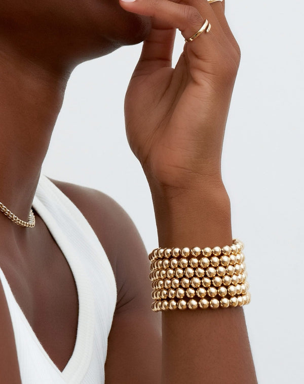Six Jumbo Gold Bead Bracelets worn on wrist of model