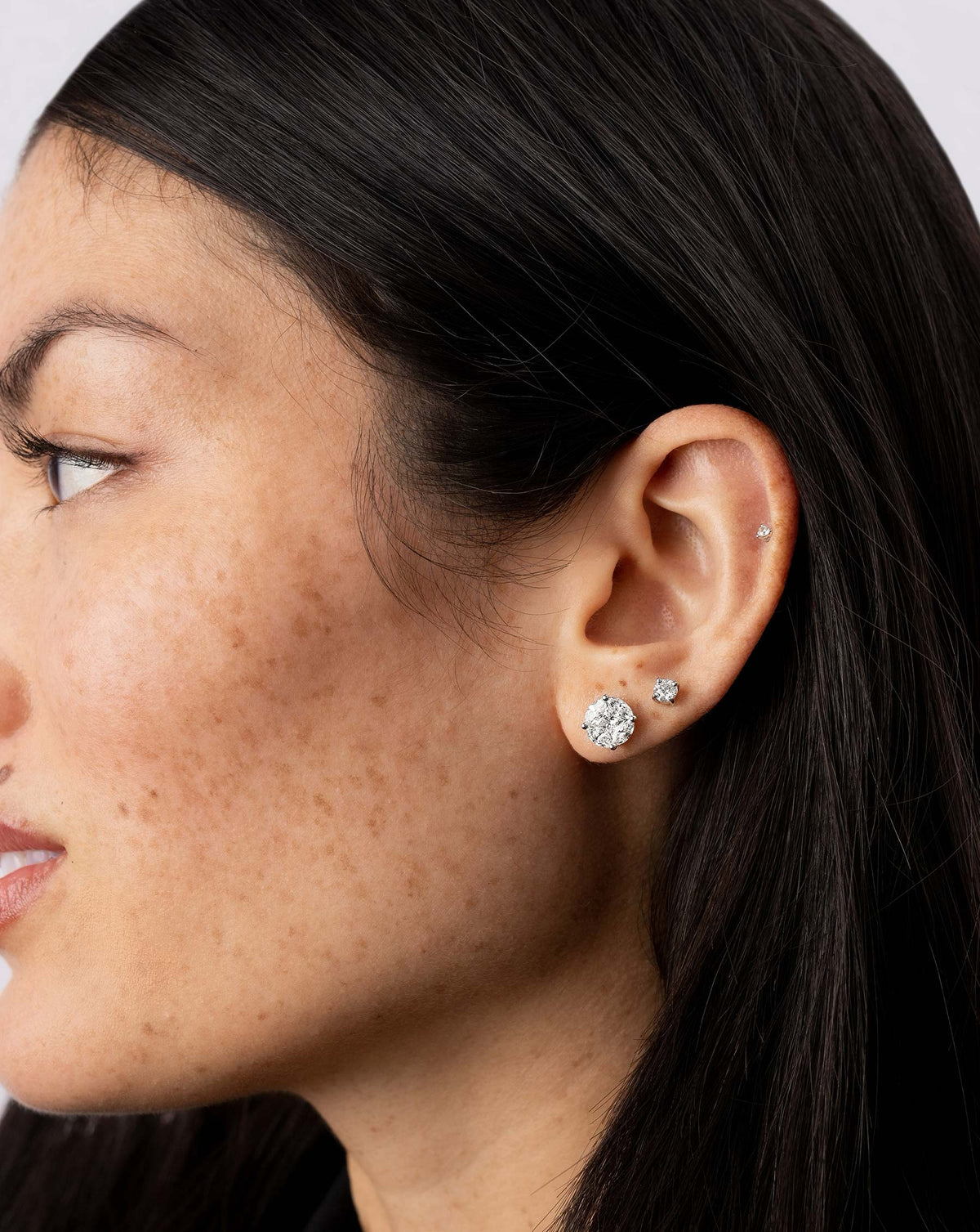 Round illusion studs stacked on ear with classic diamond studs and tiny diamond studs on model