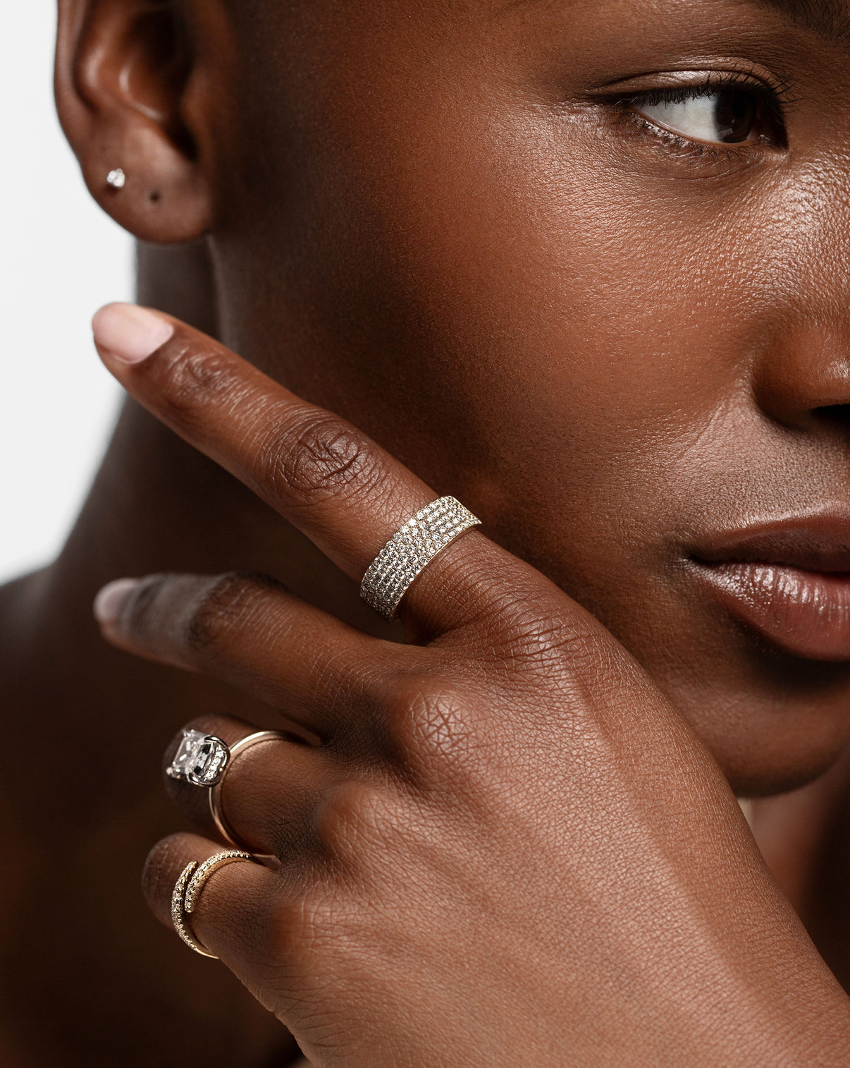 gold and diamond five row diamond ring, radiant cut diamond engagement ring, and diamond and gold wrap ring on model