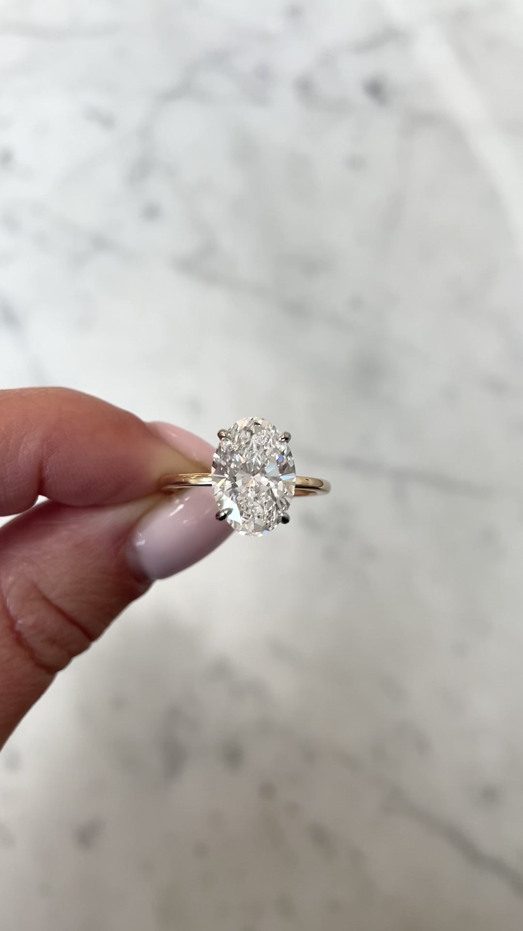 Lab Grown Oval Whisper Thin® Hidden Halo hand holding ring side view