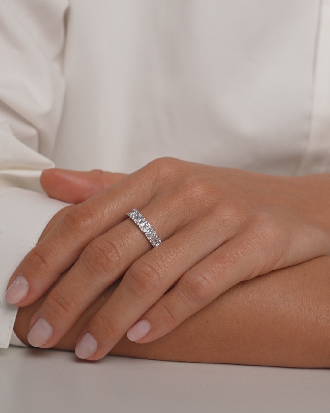 Video of Petite Emerald Illusion Ring in 14k White Gold on finger of hand resting on an arm and touching upper arm wearing the Starry Night Ring in 14k White Gold