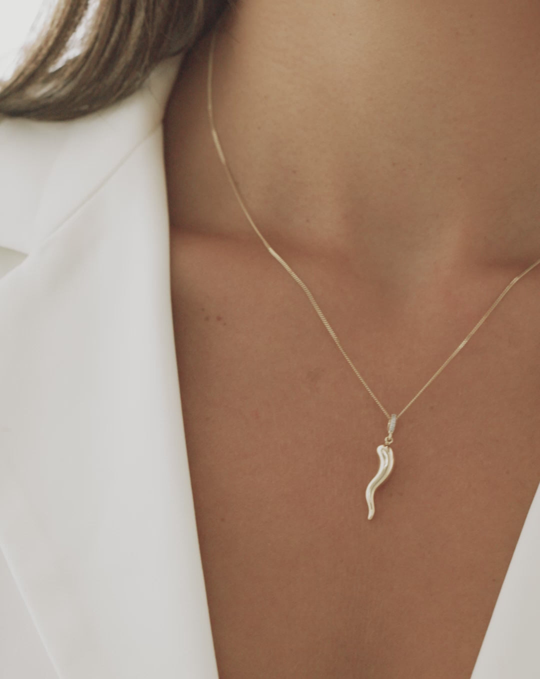 video of Cornicello Charm shown on diamond cut curb chain necklace on model's neck