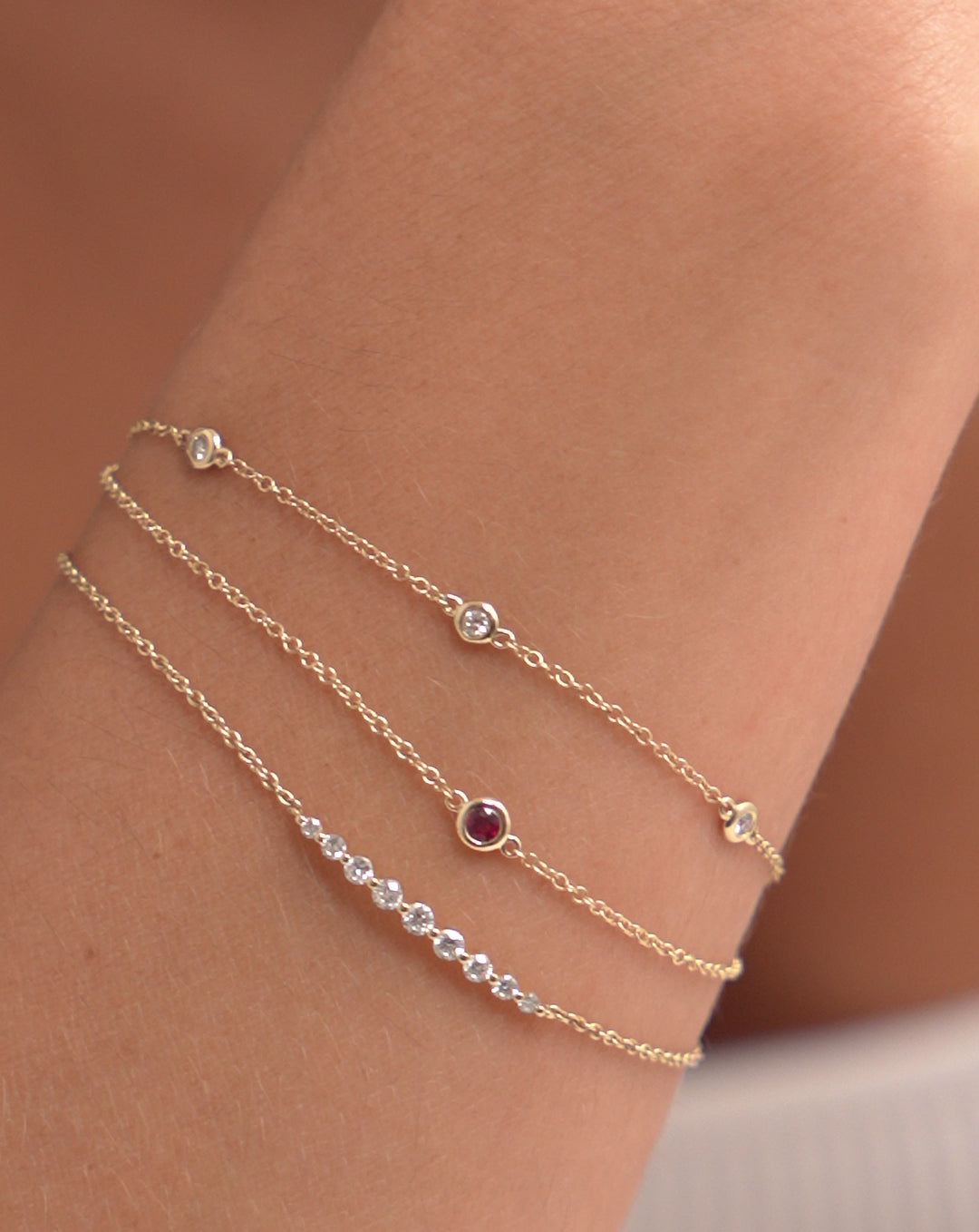 Video of the Diamond Bezel-Set Station Bracelet worn on wrist of model with the Gemstone Bezel Set Bracelet and the Graduated Single Prong Diamond Bracelet. - global