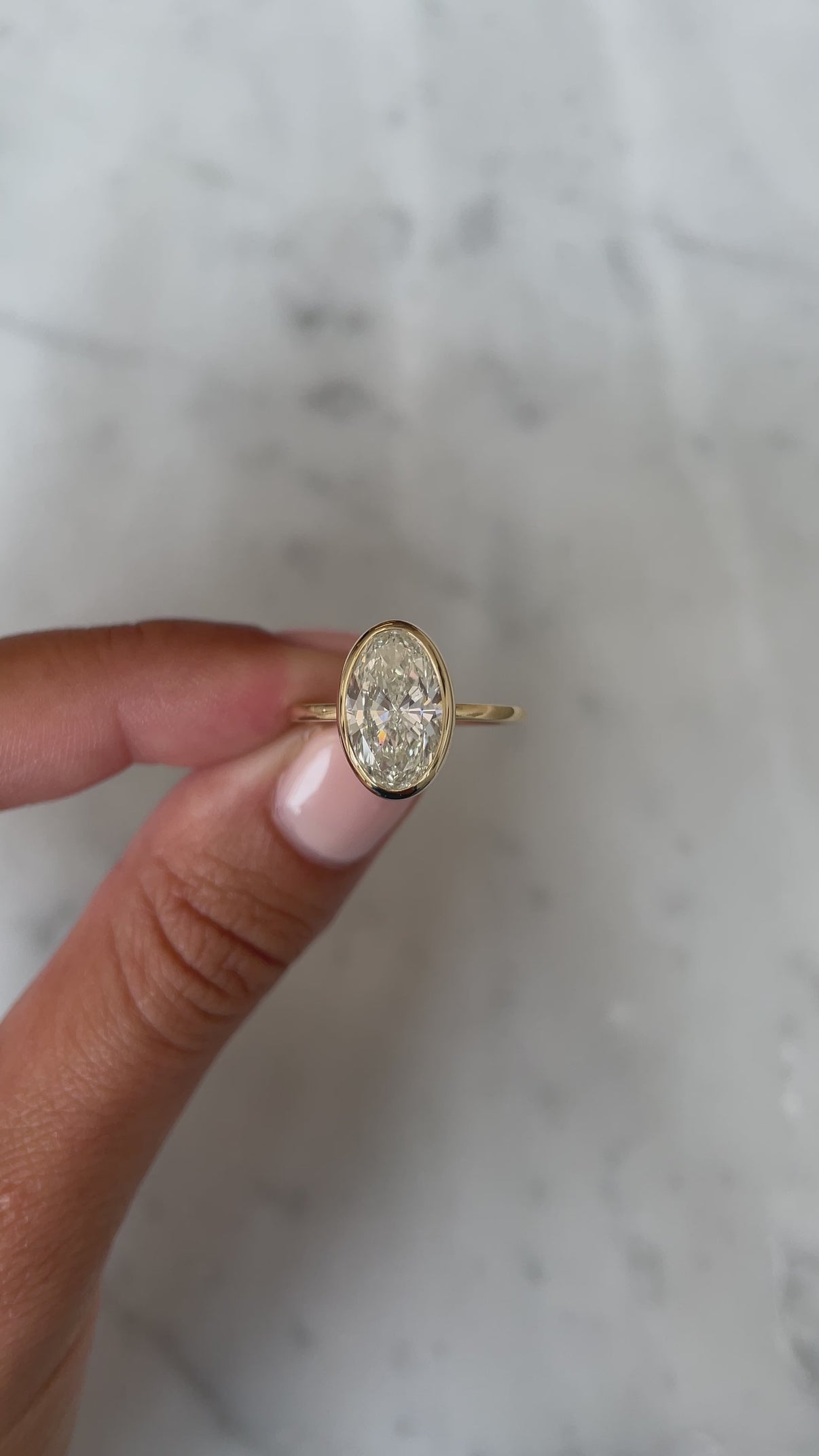 Video of 2.50 Oval in the Whisper Thin® Bezel Natural Diamond Ring 14K Yellow Gold held by model showing the front view
