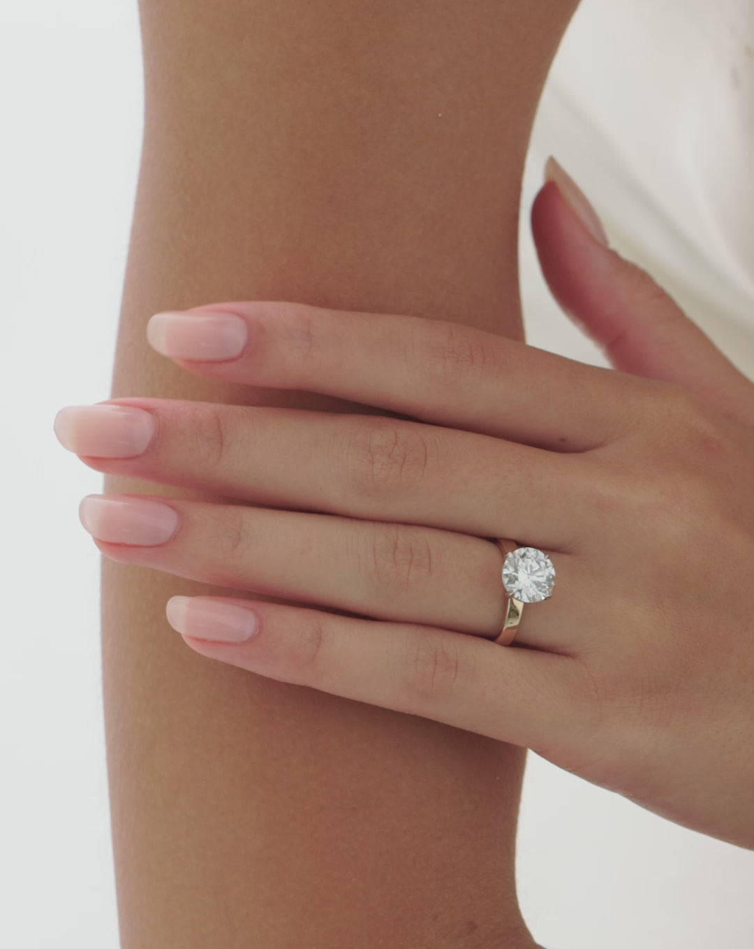 Video of a hand resting on the forearm, showcasing a gold engagement ring with a round diamond in a cigar-style band. 44829996843096 44830238900312 44830239129688 