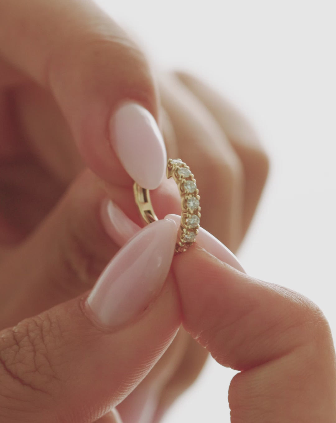 Video close-up of a 14k yellow gold jumbo diamond ear cuff held between fingers, highlighting its row of round-cut diamonds and curved design.