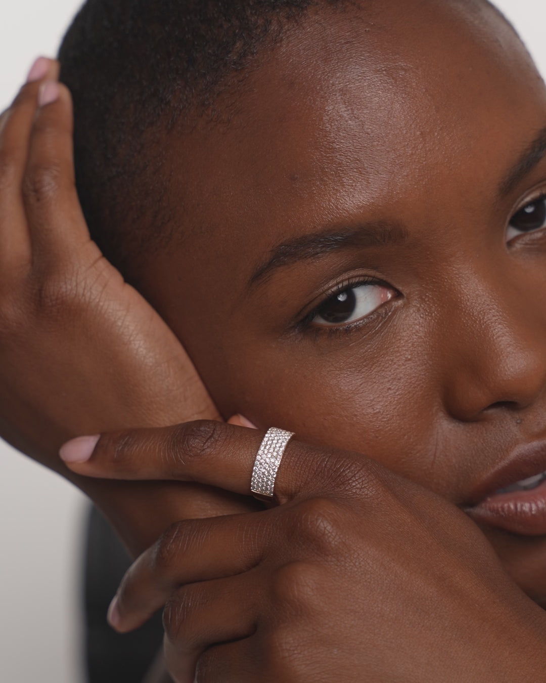 Five Row Stackable Pavé Ring in 14k Yellow Gold on pointer finger of hand touching model's face and wrist